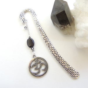 May include: Silver bookmark with a dragon head, a black stone bead, and a silver charm with the Om symbol.