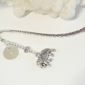 May include: Silver bookmark with a silver elephant charm and a silver disc with the letter 'S' engraved on it.