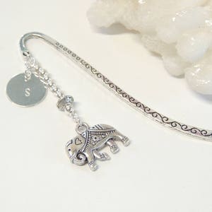 May include: Silver bookmark with a silver elephant charm and a silver disc with the letter 'S' engraved on it.