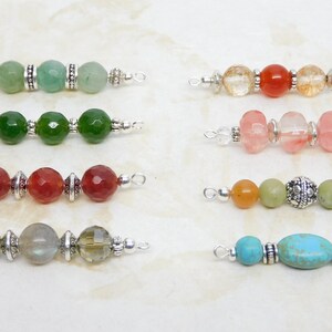 May include: A collection of beaded jewelry components, each featuring a unique combination of colorful gemstones and silver-toned metal accents. The beads vary in shape and color, including green, red, orange, and turquoise, offering a diverse range of design options.