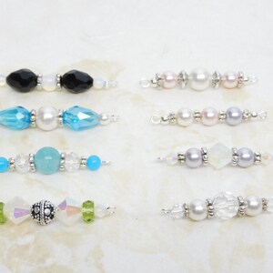 May include: A collection of beaded jewelry components, each featuring a unique design. The components include various colors of beads, including black, blue, pink, and clear, with silver-toned metal accents. These components are ideal for creating custom jewelry pieces.