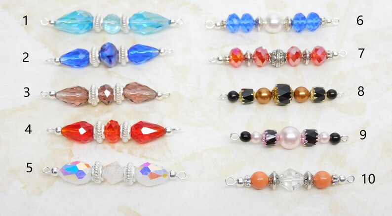 May include: A collection of ten beaded jewelry components, each featuring a unique arrangement of colorful beads. The beads include various shapes and colors, such as blue, red, brown, and iridescent, with silver-toned metal accents.