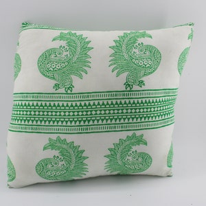 May include: Square white pillow with a green peacock print. The design features repeating peacock motifs and a decorative border. The pillow is a square shape and appears to be made of a soft fabric.