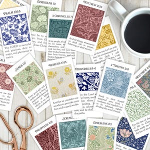 May include: A collection of rectangular cards featuring various floral patterns and Bible verses, including Psalm 108:8, Matthew 21:22, and Hebrews 10:24. The cards are arranged in a scattered layout alongside a white coffee mug and rose gold scissors.