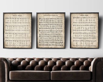 May include: Three vintage-style framed prints of Christmas carol sheet music. The titles are "O Holy Night", "Hark the Herald Angels Sing", and "Silent Night".
