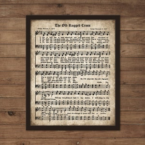 May include: A vintage sheet music print of the hymn "The Old Rugged Cross" by George Bennard. The sheet music features the lyrics and musical notation for the song. The paper is aged and has a yellowed hue.