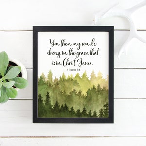 Op de afbeelding: Een ingelijst afdruk met een aquarel van een bos met een citaat uit de Bijbel: "Wees dan sterk, mijn zoon, in de genade die in Christus Jezus is." 2 Timoteüs 2:1