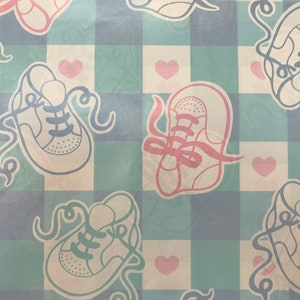 May include: A blue and white checkered pattern with a repeated design of white baby shoes with pink and blue laces. The background is a light blue and white checkered pattern with pink hearts.