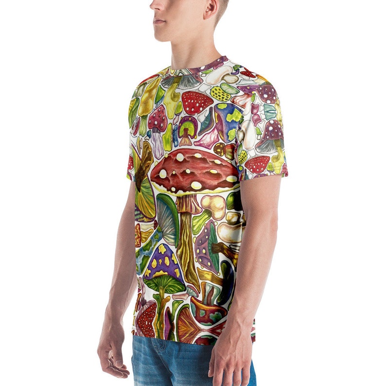 K&ouml;nnte beinhalten: Ein wei&szlig;es T-Shirt mit einem bunten Allover-Druck aus verschiedenen Pilzen. Die Pilze sind in verschiedenen Formen, Gr&ouml;&szlig;en und Farben, darunter Rot, Gelb, Gr&uuml;n, Lila und Braun.