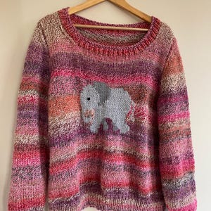 May include: A pink, purple, and orange striped knitted sweater with a gray elephant design on the front.