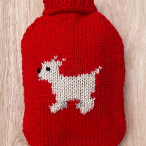 Op de afbeelding: Rode gebreide kruikhoes met een wit gebreid hondenontwerp.