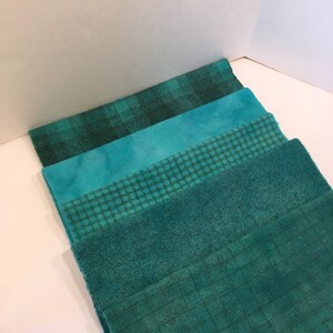 May include: Five different teal fabric swatches with various patterns, including plaid, tie-dye, polka dots, and woven textures.