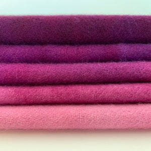 May include: Five pieces of fabric in shades of purple and pink, stacked on top of each other. The fabric is a soft, textured material.