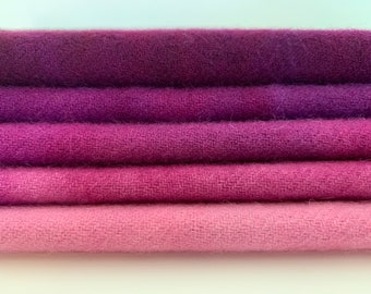 May include: Five pieces of fabric in shades of purple and pink, stacked on top of each other. The fabric is a soft, textured material.