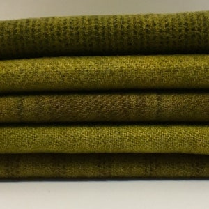 May include: A stack of five different shades of green fabric swatches. The fabric is a woven wool blend with a subtle texture.