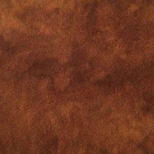 May include: A close-up of a brown suede fabric with a slightly mottled texture.