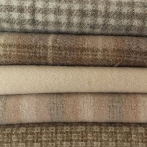 May include: A stack of five different patterned fabric swatches in shades of brown, beige, and white. The fabrics are soft and textured, with a variety of weaves and patterns.
