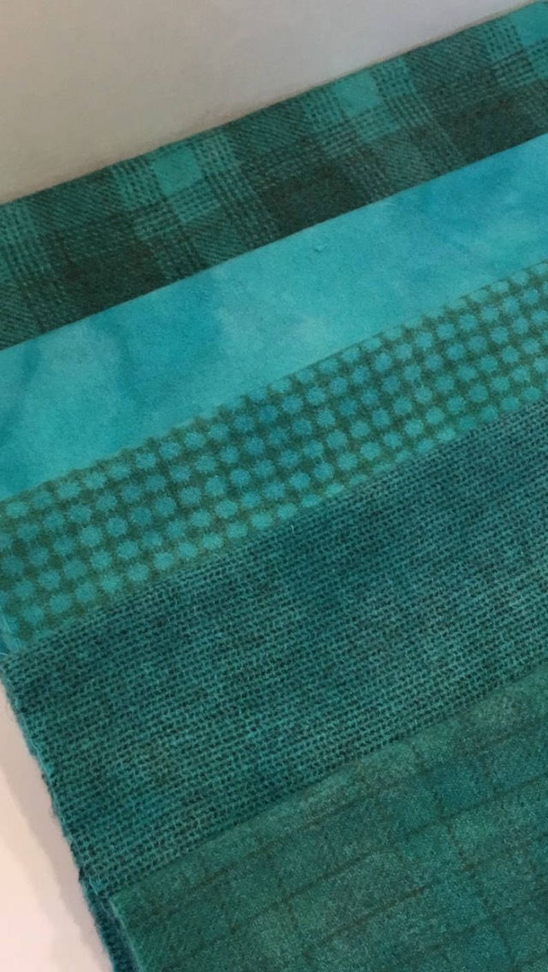 May include: Four different teal fabric swatches with various patterns. The top swatch is a plaid pattern, the second is a solid colour, the third is a small dot pattern, and the bottom is a woven burlap fabric.