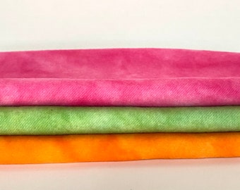 May include: Three fabric swatches stacked on top of each other. The top swatch is pink, the middle swatch is green, and the bottom swatch is orange.