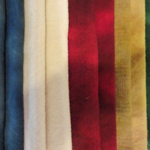 May include: A collection of eight fabric swatches in various colours, including blue, white, red, yellow, and green. The fabric swatches are arranged in a row, with the blue swatches on the left and the green swatches on the right.