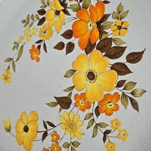 May include: Round, off-white ceramic plate with a brown rim and a floral design. The flowers are yellow and orange with brown leaves. The plate has a diameter of approximately 12 inches.