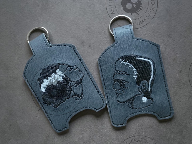 Pu&ograve; includere: Due portachiavi grigi con anelli argentati. Un portachiavi presenta un'immagine ricamata della sposa di Frankenstein, l'altro il mostro di Frankenstein. La parola "HANDMADE" &egrave; ricamata su un portachiavi.