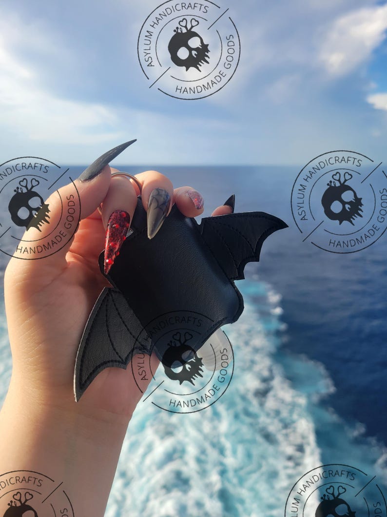 Puede incluir: Un llavero de piel sint&eacute;tica negra con forma de murci&eacute;lago y alas extendidas. El accesorio cuenta con una anilla met&aacute;lica en la parte superior. El dise&ntilde;o es de color negro s&oacute;lido con bordes cosidos, mostrando una silueta de murci&eacute;lago.