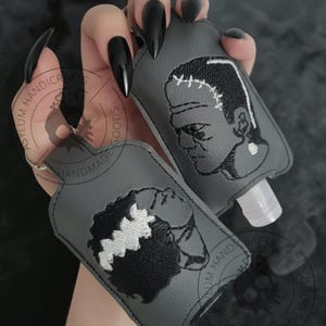 Pu&ograve; includere: Due porta igienizzanti mani grigi con ricami in bianco e nero di Frankenstein e della sposa di Frankenstein. Ogni porta igienizzante ha un portachiavi argentato e un flacone di plastica trasparente.