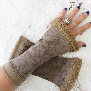 May include: A pair of brown fingerless gloves with a patterned design and a faux fur trim. The gloves are made of a soft material and are designed to keep hands warm while leaving fingers free.