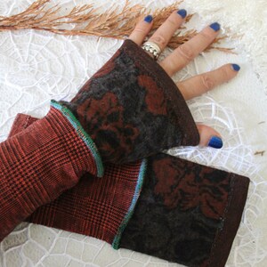 May include: A pair of brown and black fingerless gloves with a floral pattern. The gloves have a green and blue trim.
