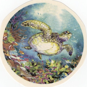 Puede incluir: Adhesivo redondo que muestra una escena submarina con una tortuga marina nadando entre corales y peces coloridos. La tortuga tiene un caparazón verde y amarillo, con un fondo azul claro.