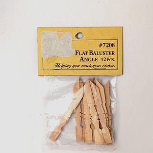 May include: A package of 12 light brown wooden flat balusters with pointed tops. The yellow cardboard header displays the text #7208 FLAT BALUSTER ANGLE 12 PCS. Helping you reach your vision. The items are contained within a clear plastic bag.