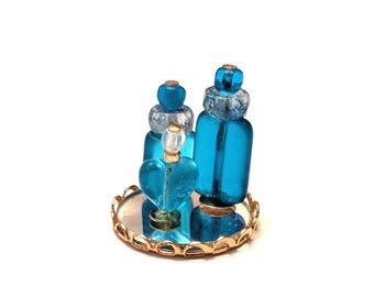 Botellas de perfume azul brillante en bandeja para casa de muñecas en miniatura