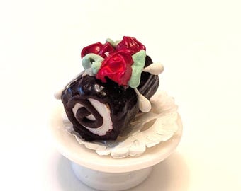 Pastel de chocolate en miniatura para casa de muñecas sobre soporte de porcelana
