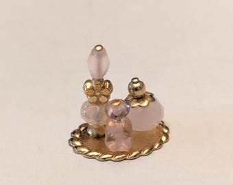 Frascos de perfume rosa en miniatura para casa de muñecas sobre bandeja