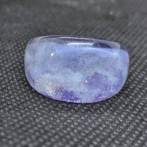 Puede incluir: Un anillo de resina morado y blanco con un efecto nublado y veteado.