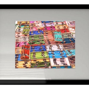 May include: A close-up view of a variety of colorful embroidery floss spools arranged in rows. The spools are organized by color, creating a vibrant and colorful display.