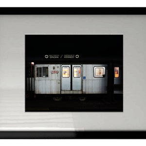 Może przedstawiać: Biały pociąg metra z napisem "Next Station Spadina / Eastbound to Kennedy" wyświetlonym nad drzwiami. Pociąg stoi na stacji, a drzwi są zamknięte.