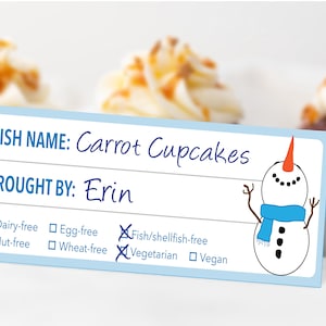 May include: A light blue table tent card with the text "DISH NAME: Carrot Cupcakes" and "BROUGHT BY: Erin." A snowman illustration is on the right. The card indicates the cupcakes are nut-free, fish/shellfish-free, and vegetarian.