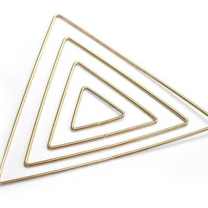 May include: Four gold-colored metal triangles of different sizes, nested inside each other, forming a geometric pattern.