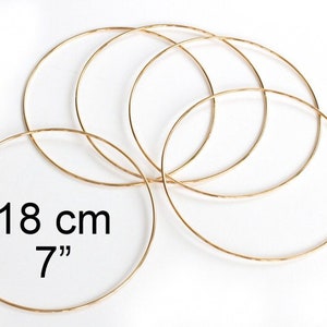 May include: Five gold-colored metal hoops of varying sizes. The largest hoop measures 7 inches or 18 cm in diameter.