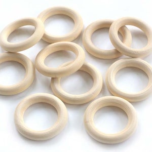 May include: A set of ten unfinished wooden rings, perfect for crafting projects. The rings are all the same size and are made of natural wood.