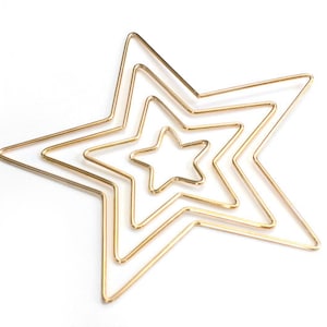 May include: Three gold metal star-shaped hoops, nested inside each other, on a white background.