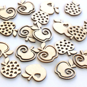 May include: A collection of wooden apple-shaped ornaments with various designs, including a swirl, a heart, and a pattern of small hearts. The ornaments are made of natural wood and have a light brown color.