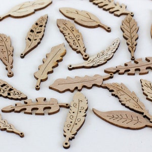 May include: A collection of wooden feather charms with various designs and patterns. The charms are made of light brown wood and have a hole at the top for hanging.