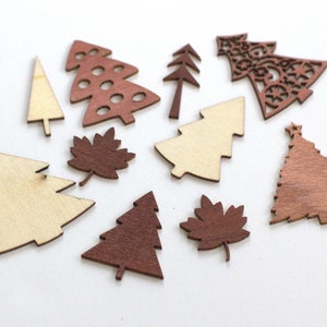 May include: Assortment of wooden Christmas tree ornaments in various sizes and colors. The ornaments are made of natural wood and have a rustic, handcrafted look. Some ornaments are plain wood, while others are painted in shades of brown and red.