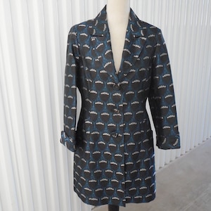 May include: A black and blue patterned blazer with a long, fitted silhouette. The blazer has a v-neck, long sleeves, and a button closure.