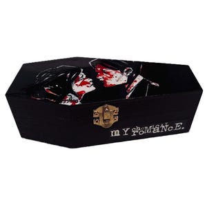 May include: Black coffin-shaped box with a hinged lid and a gold-coloured clasp. The lid features a graphic of two figures kissing with red accents. The text "my chemical romance" is printed on the front.