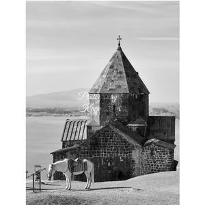 May include: Black and white photograph of a stone church with a cross on top, a white horse with a saddle, and a body of water in the background. The text "Lake Sevan, Armenia 2025" is at the bottom.