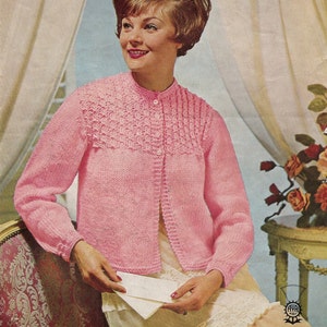 May include: A pink knitted cardigan with a button fastening and a delicate lace pattern on the front. The cardigan has long sleeves and a fitted silhouette.